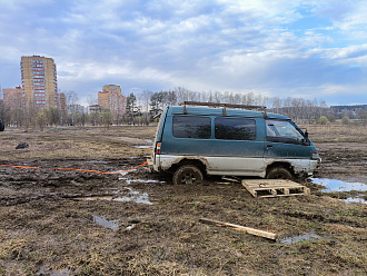 Машина застряла в поле, в 100 метрах от конечной остановки автобуса, заполнение колеса в грязи, передние в луже, есть трос динамический, есть за что цеплять вытащить застрявшую машину Mitsubishi Delica